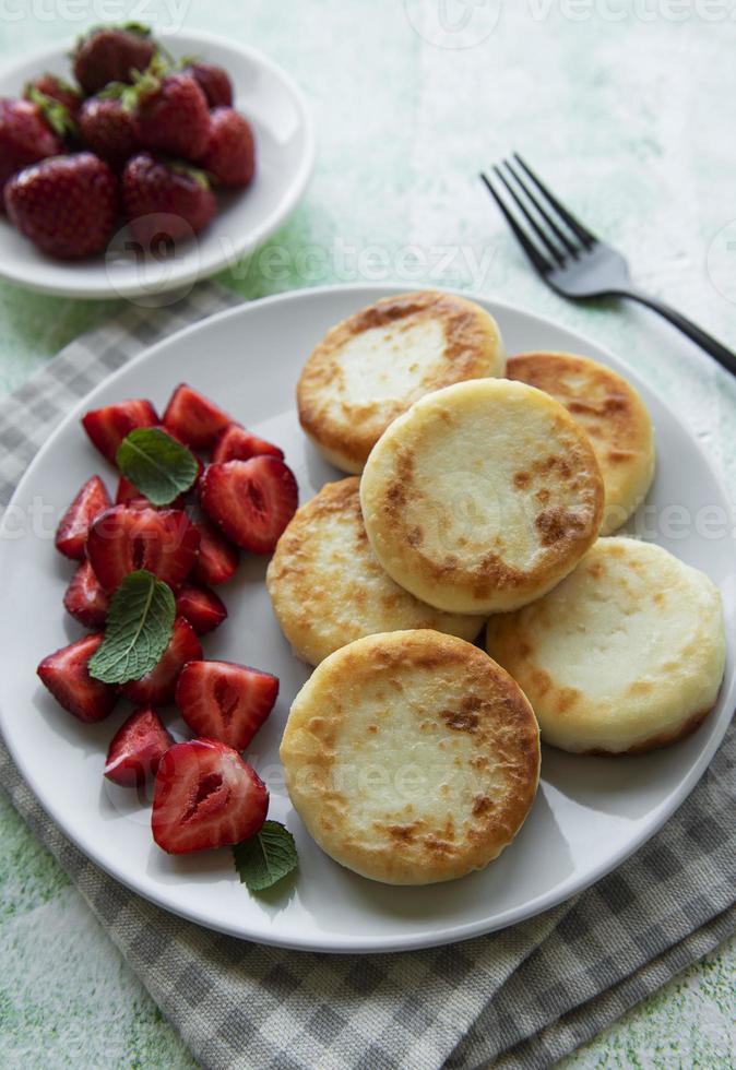 keso pannkakor, ricotta fritters på keramisk tallrik med färsk jordgubbe. foto