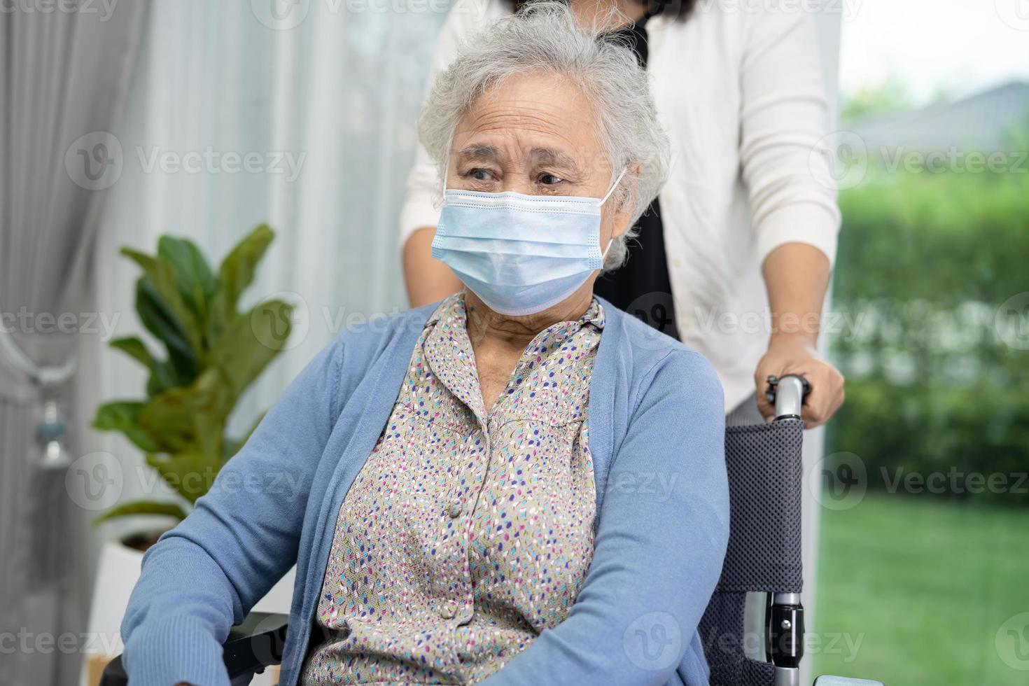 hjälp asiatisk senior eller äldre gammal dam som sitter på rullstol och bär ansiktsmask för att skydda säkerhetsinfektion covid-19 coronavirus. foto