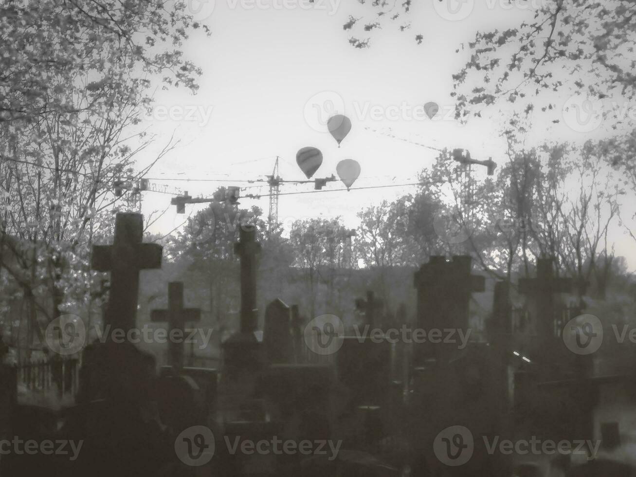 dramatisk svart och vit konstnärlig fotografera av går över av en kyrkogård och luft ballonger flygande över den och crawler kranar. foto