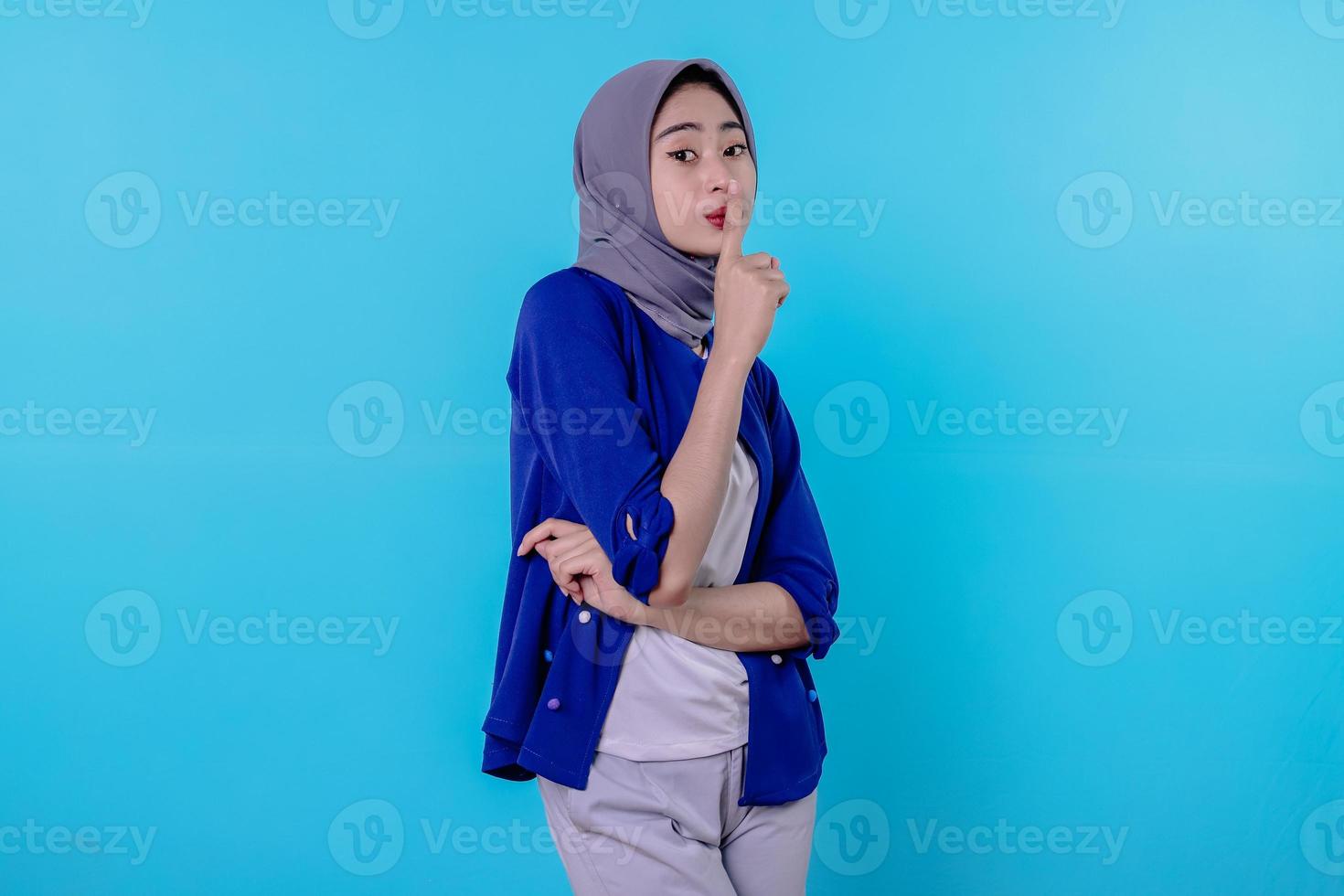 mystisk kvinna gör tystnad gest tittar bort berättar hemligt bär hijab isolerad över vit vägg foto