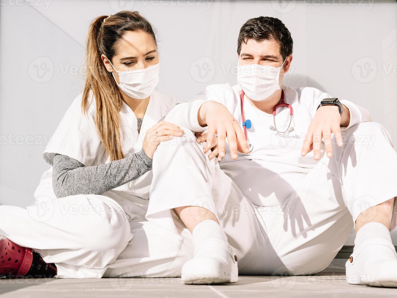 trötta läkare som sover på golvet på klinikens terrass tillsammans foto