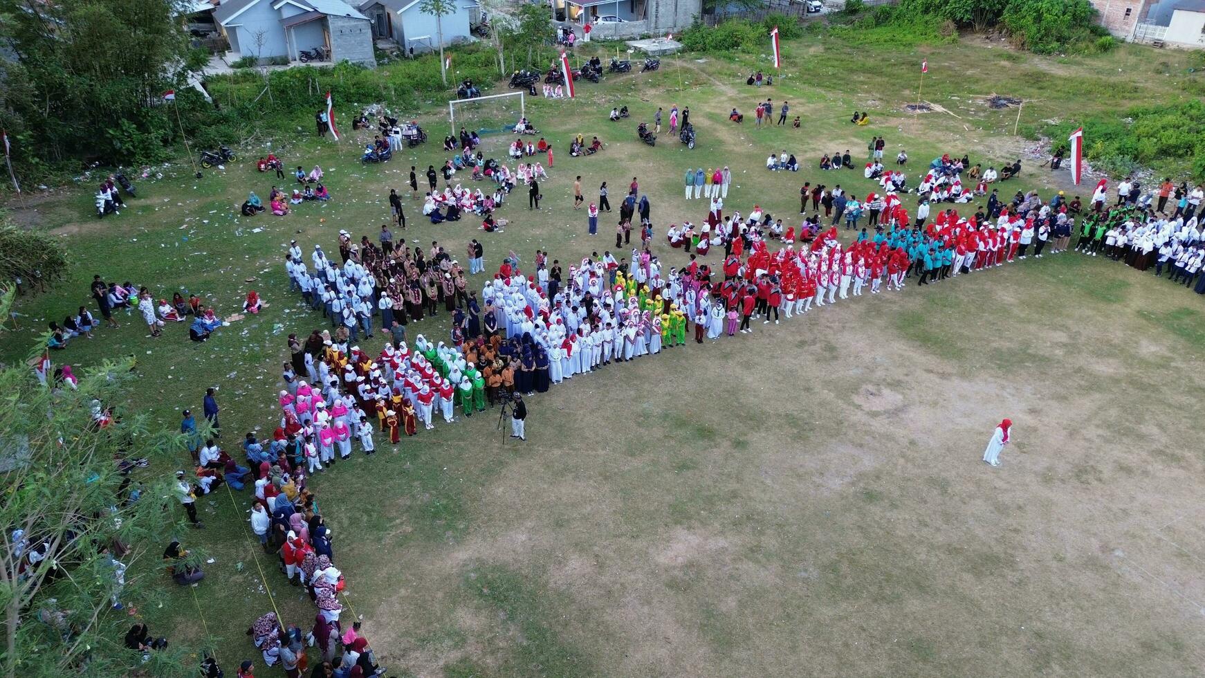 antenn se av indonesiska flagga sänkning ceremoni bevittnade förbi bybor. indonesien oberoende dag foto