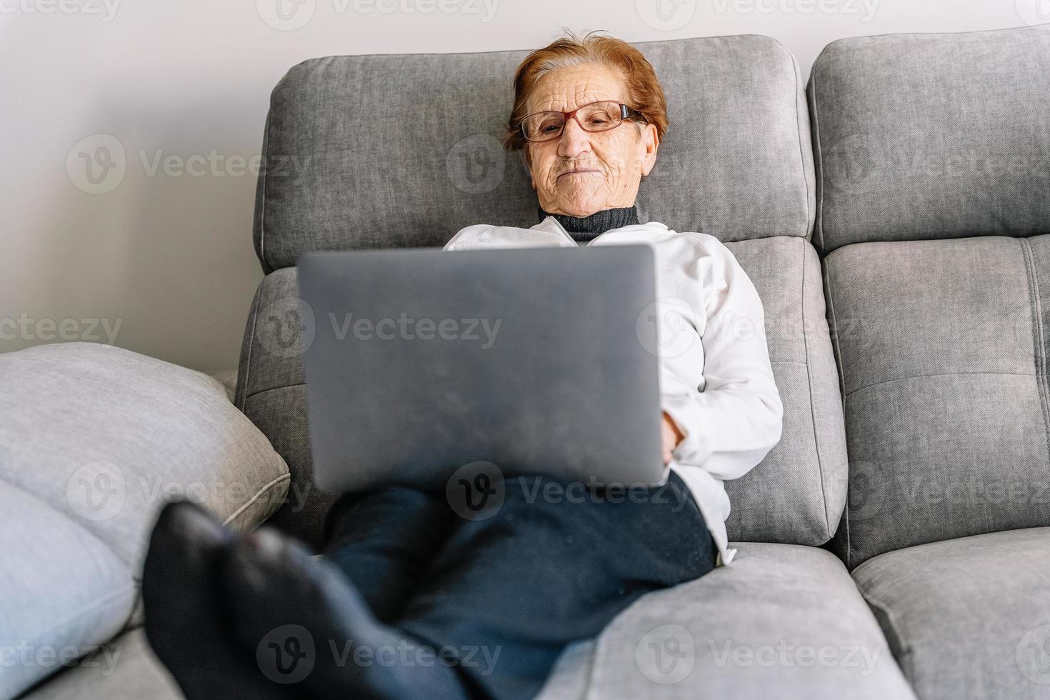 lugn senior kvinna surfa laptop i vardagsrummet foto