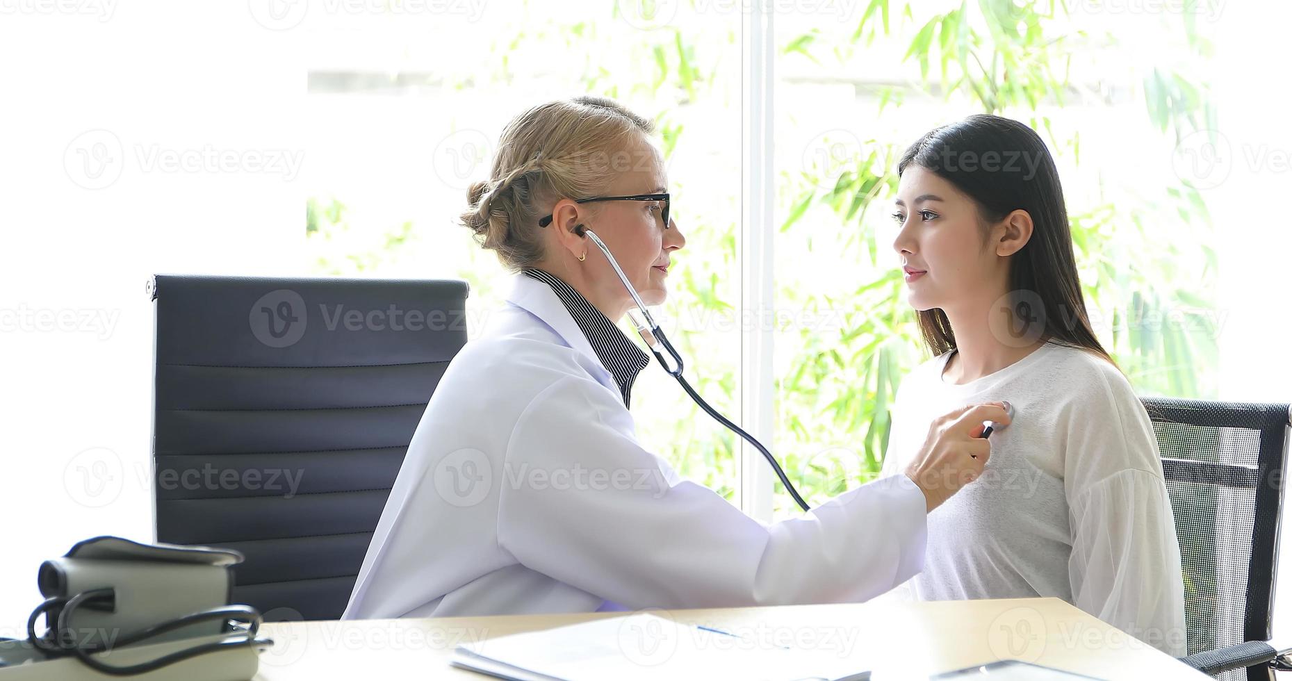 läkare som använder stetoskop för att undersöka patient på sitt kontor på sjukhus foto