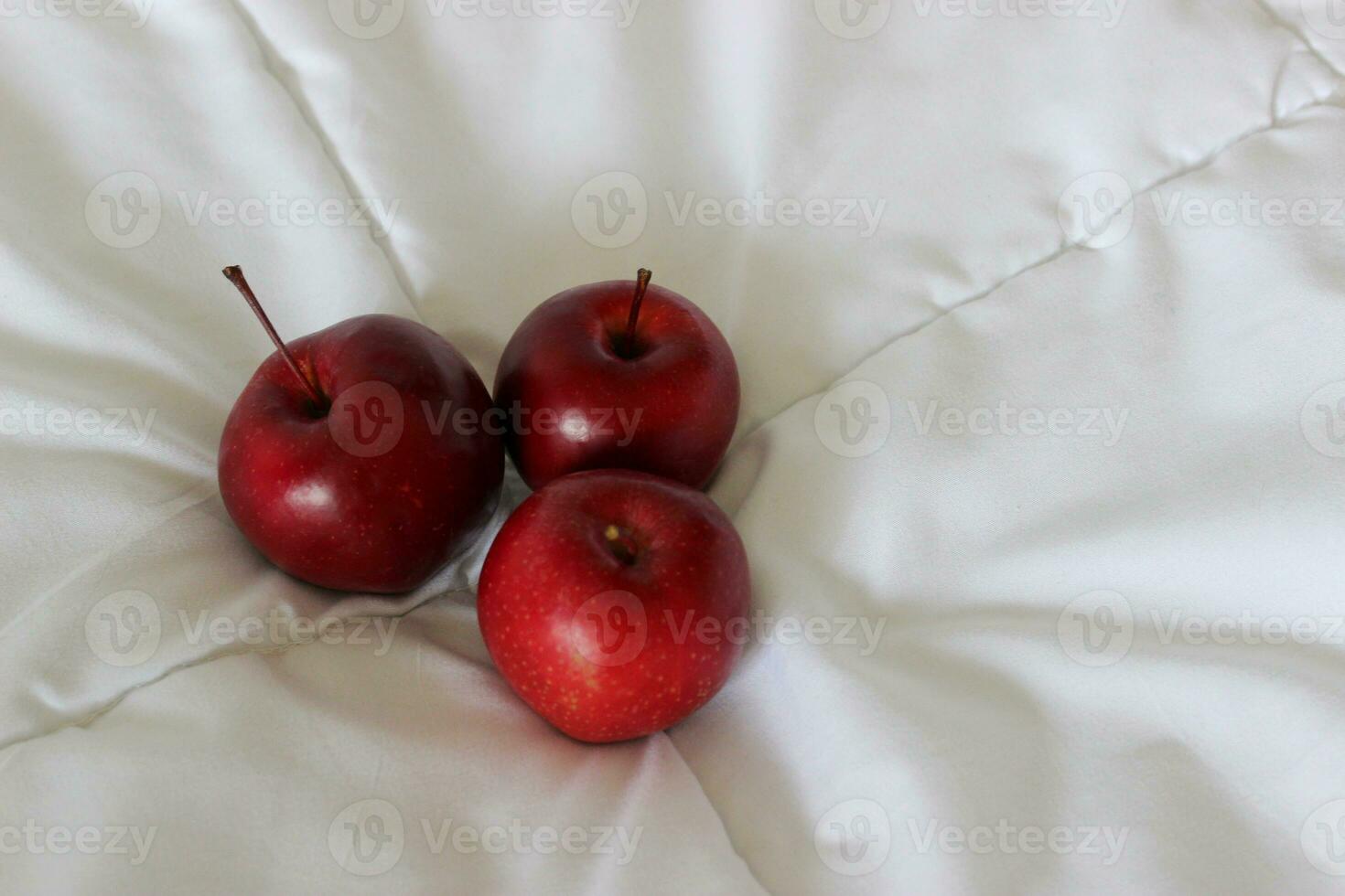 tre röd mogen äpple frukt på en vadderad filt på en sida av bild begrepp för logotyp eller titlar foto