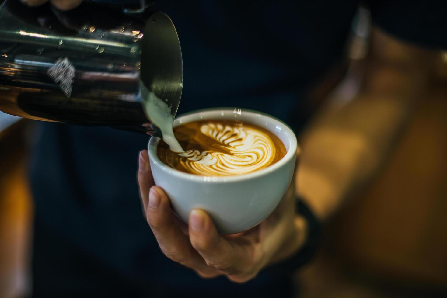 närbild av händer barista göra latte kaffe konst färg foto