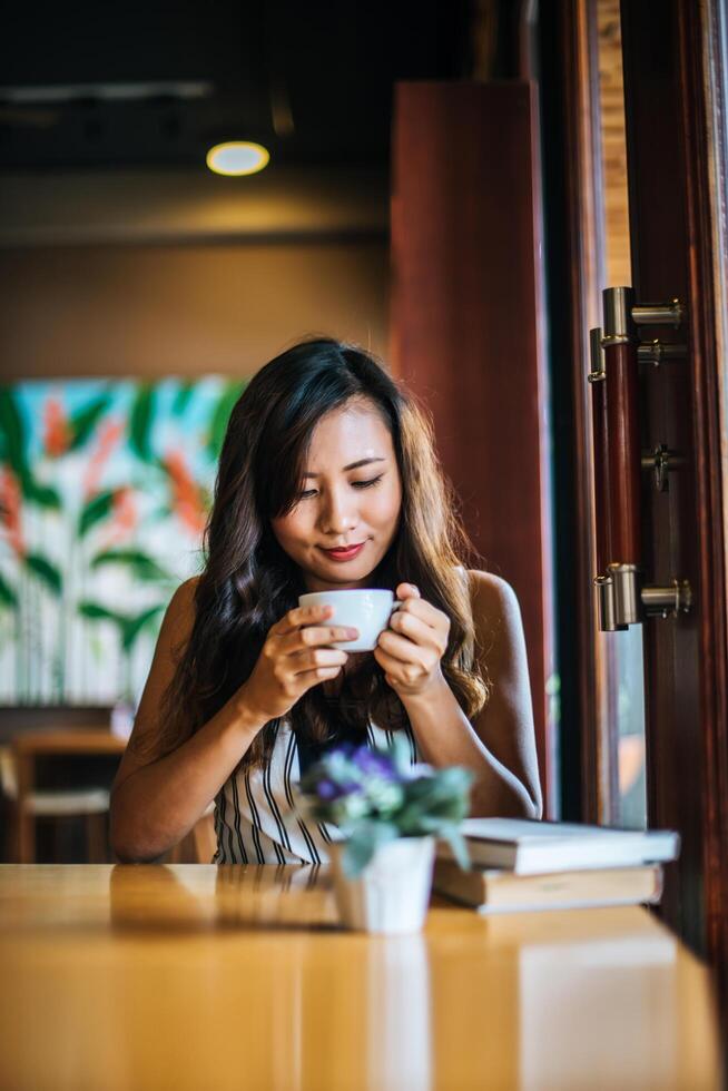 porträtt asiatisk kvinna leende slappna av i caféet foto