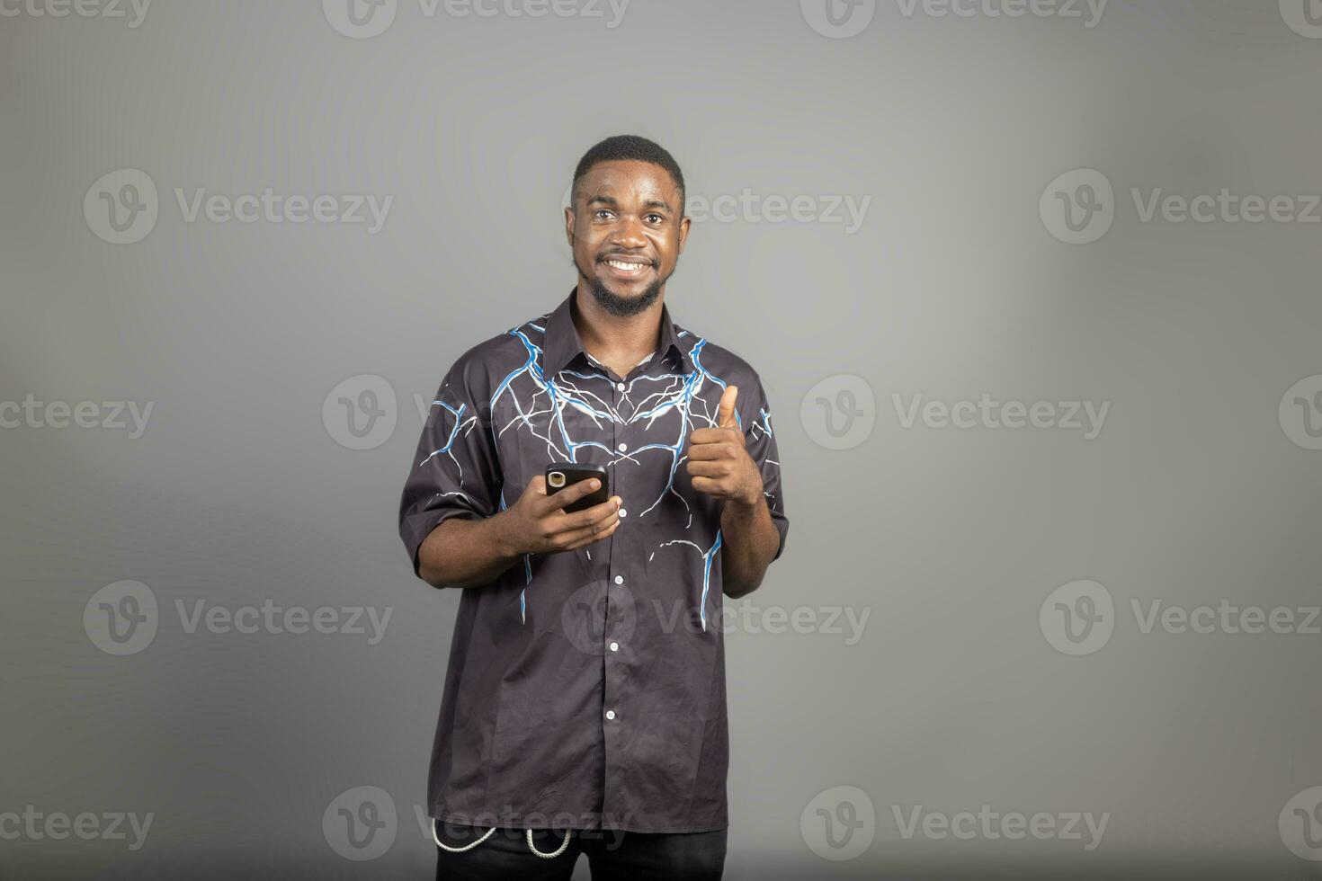 attraktiv afrikansk amerikan man textning på hans telefon isolerat över grå foto