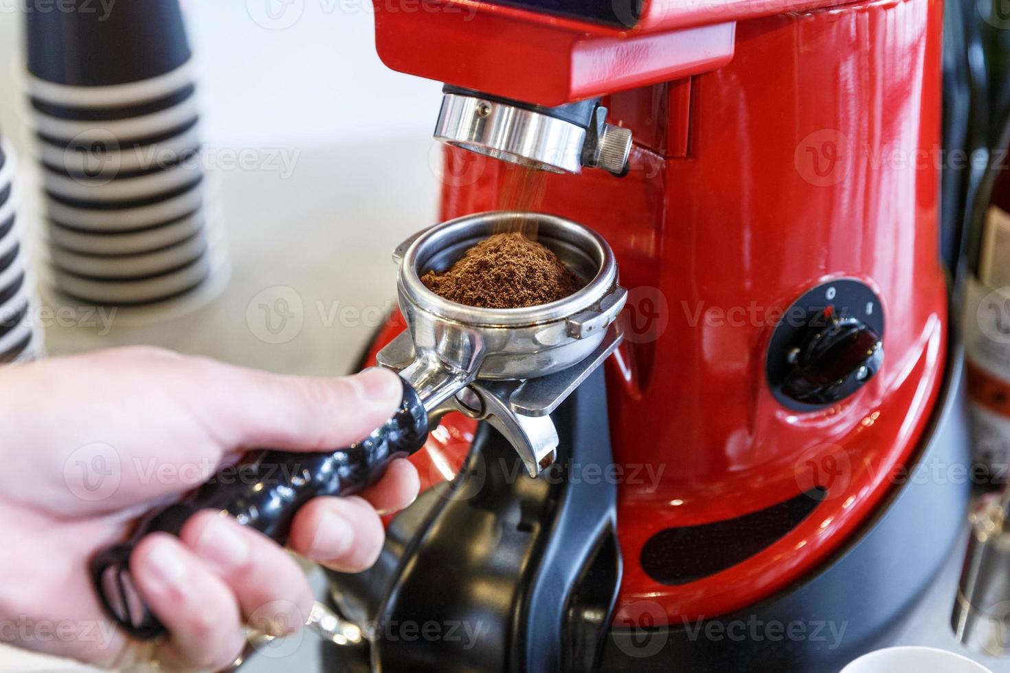 bartendern på ett kafé som maler färska kaffebönor i en kaffemaskin. foto