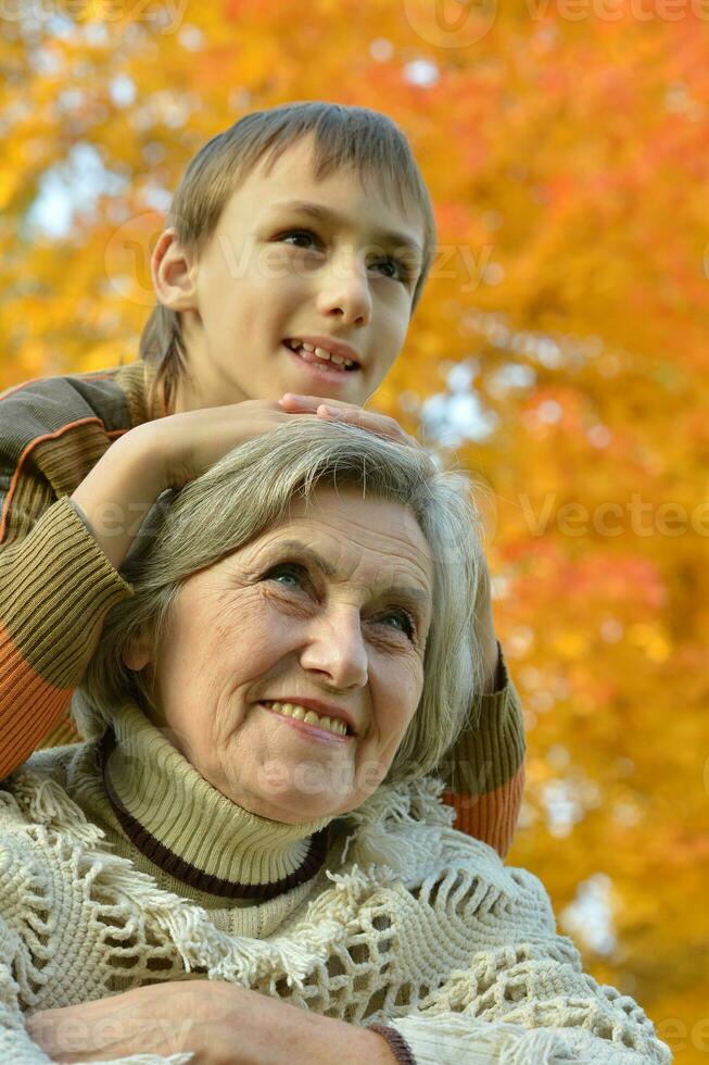 mormor med pojke vilar i de höst parkera foto