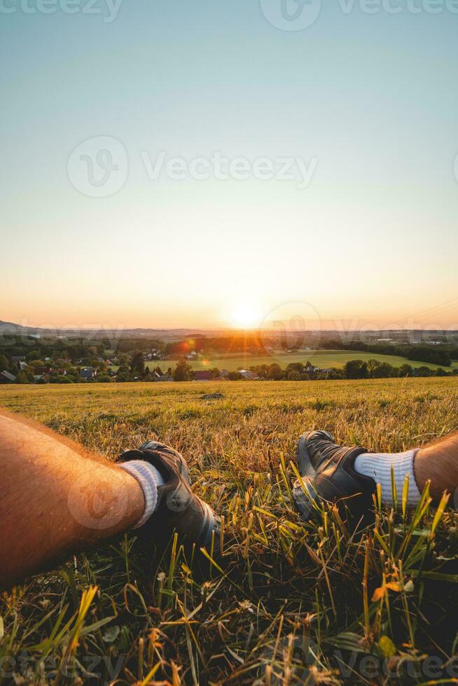 vandrarens fötter upplyst förbi de orange röd ljus från de Sol, mot de mörk himmel. beskydy berg, tjeck republik foto