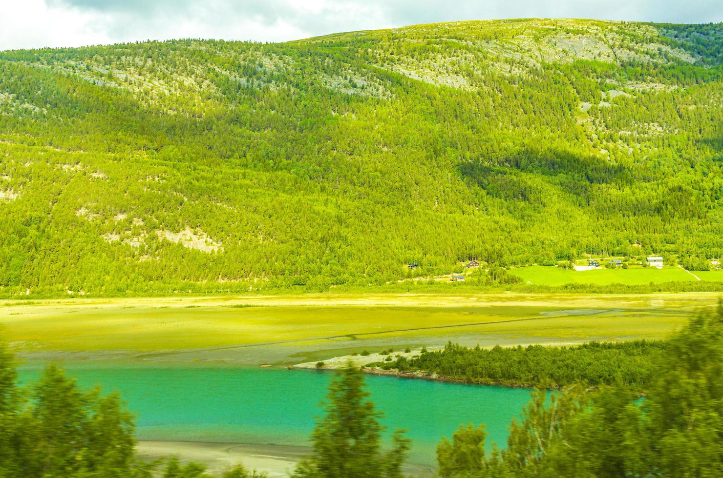 turkos smältvatten rinner i floden genom bergslandskapet i Norge foto