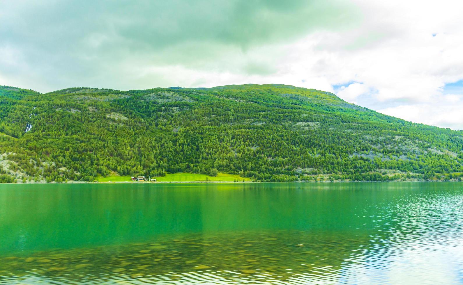 turkos smältvatten rinner i floden genom bergslandskapet i Norge foto