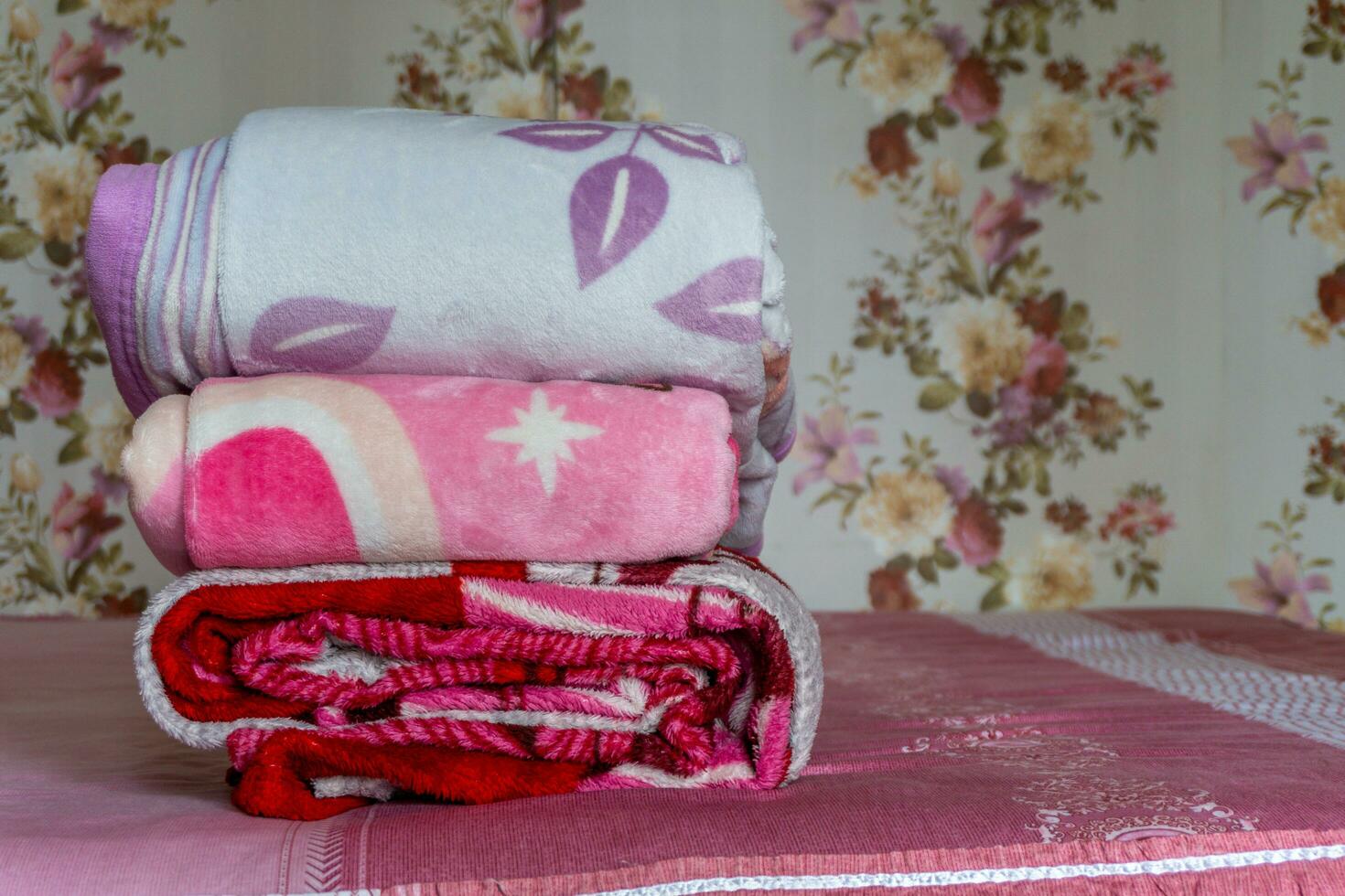 staplade av färgrik filt på rosa säng. vikta rosa filtar. vit vikta täcke liggande foto