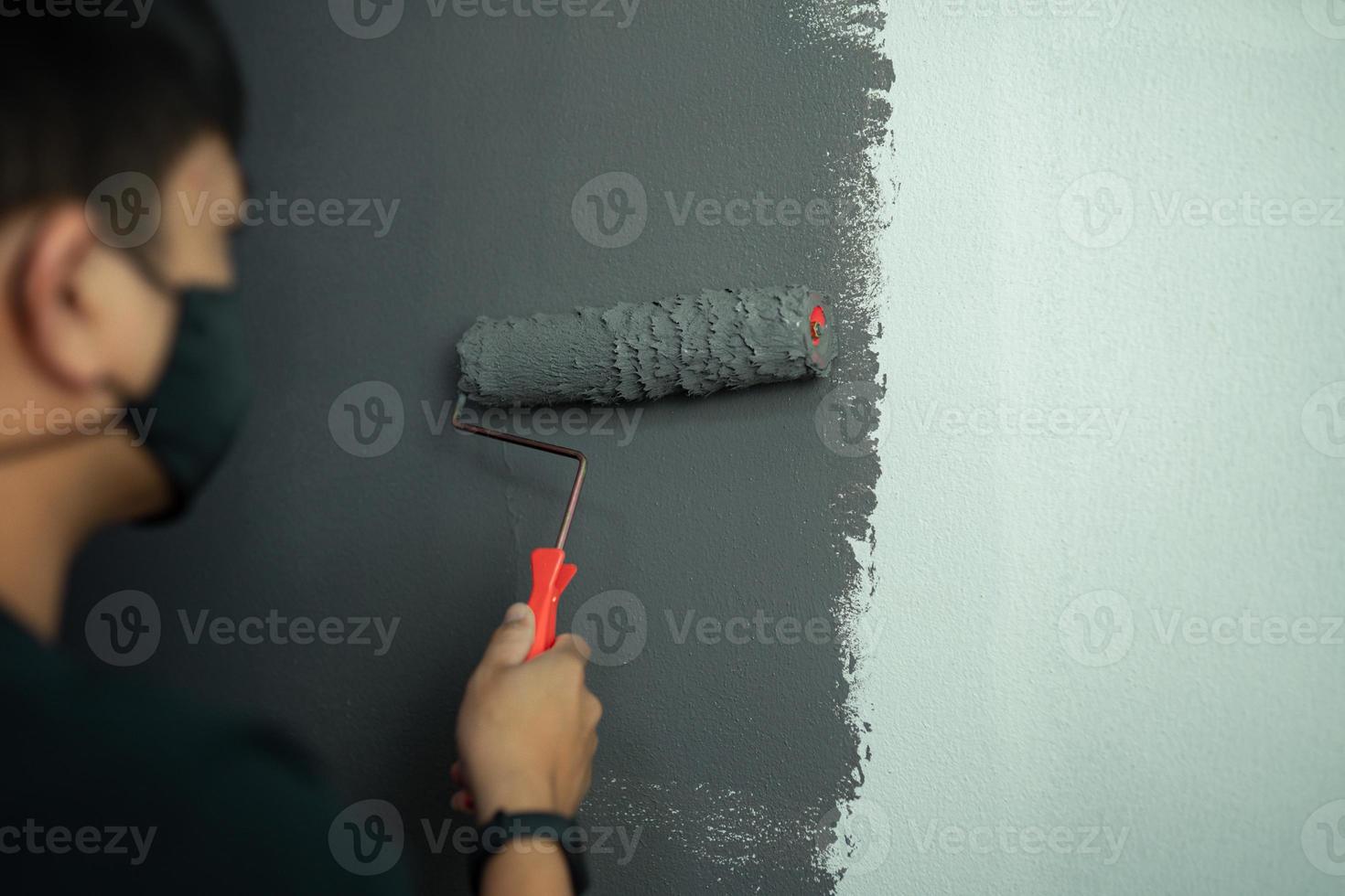 ung man målar en mörk färg inre vägg av konceptarbete hemifrån foto