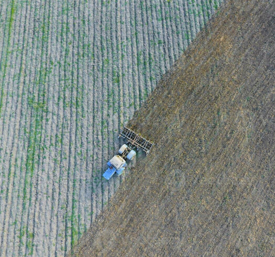 topp se av de traktor den där plogar de fält. diskning de jord. foto