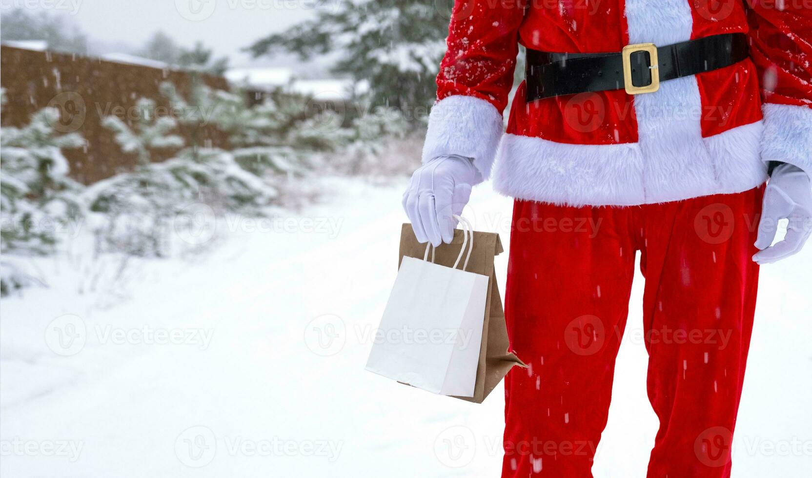 santa claus utomhus- i vinter- och snö lämnandet i hand eco papper påsar med hantverk gåva, mat leverans. handla, förpackning återvinning, handgjorda, leverans för jul och ny år foto