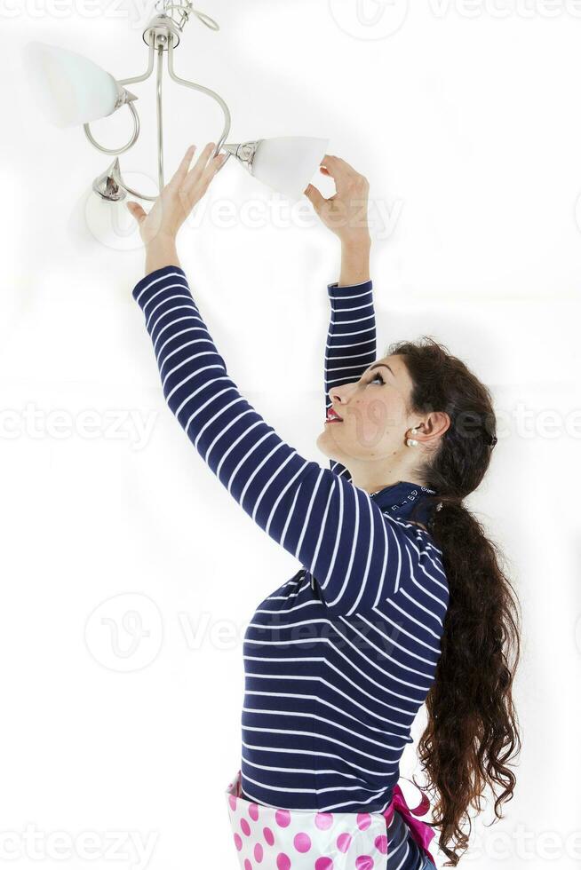 Söt kvinna montera en ny ljus Glödlampa i de uttag foto