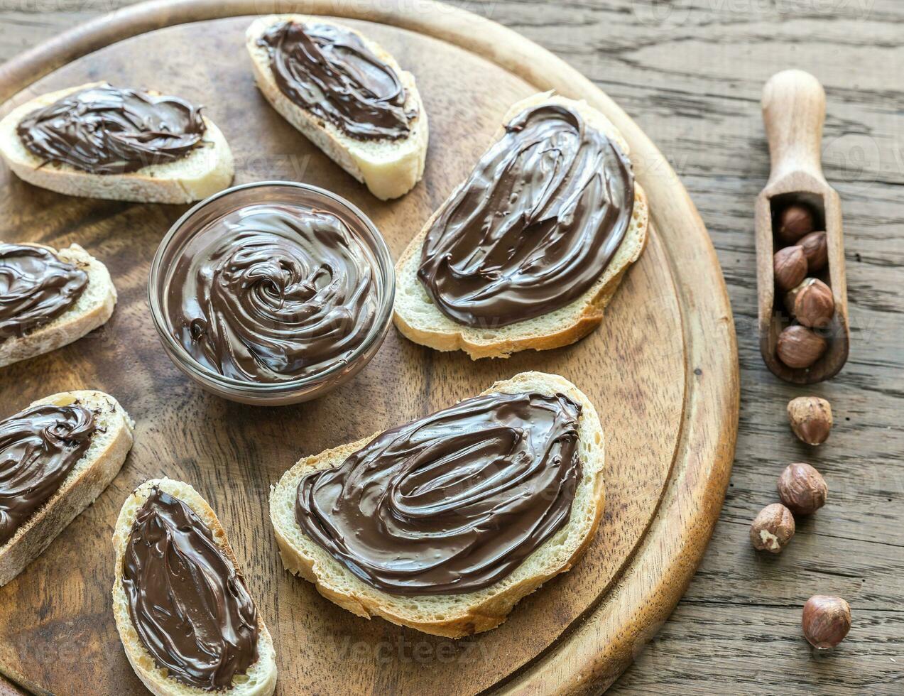 skivor av baguette med chokladkräm på träskivan foto