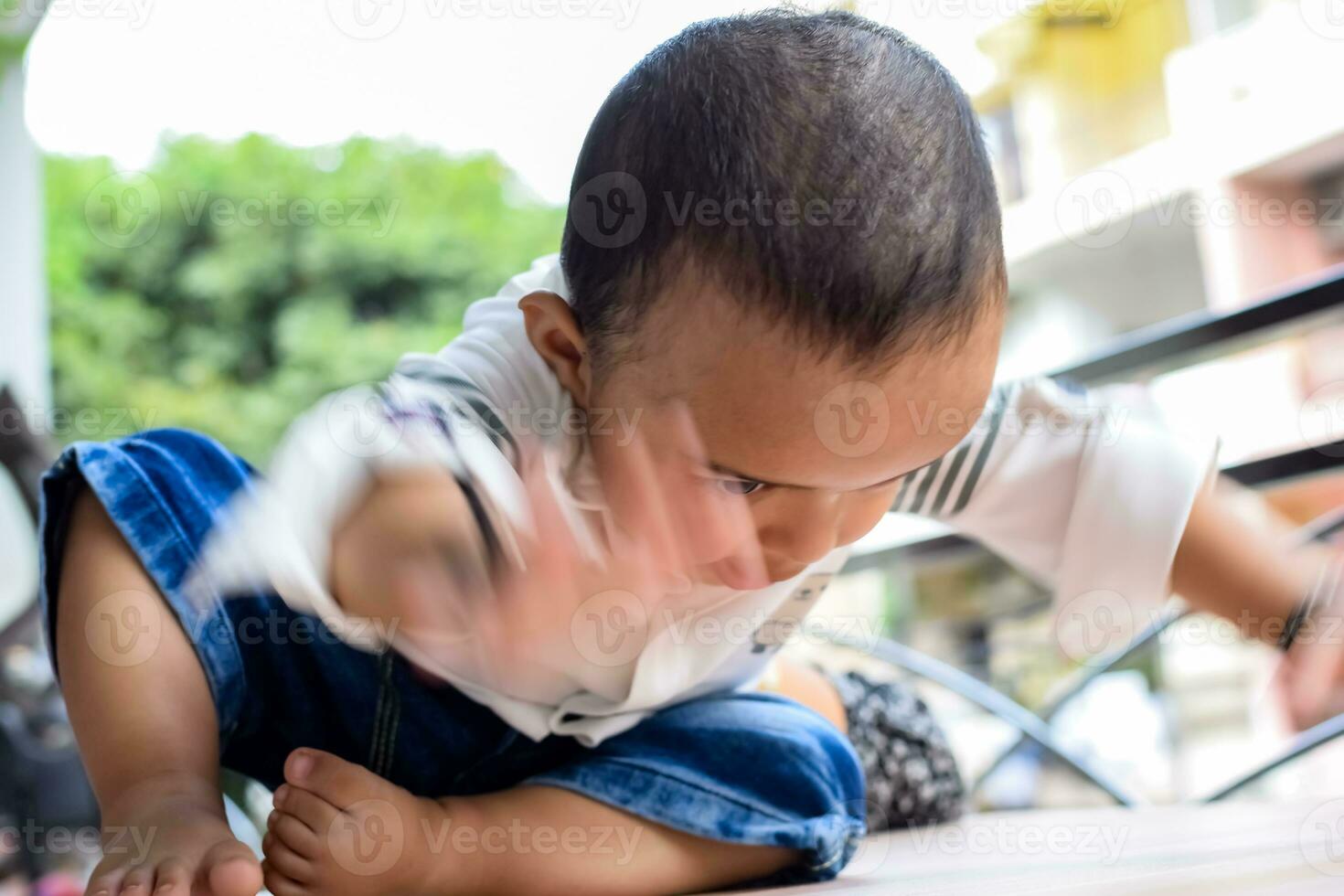 bebis pojke på Hem balkong. ljus porträtt av Lycklig barn Sammanträde på de tabell. liten 1 år gammal pojke under de dag ljus på hus balkong. foto