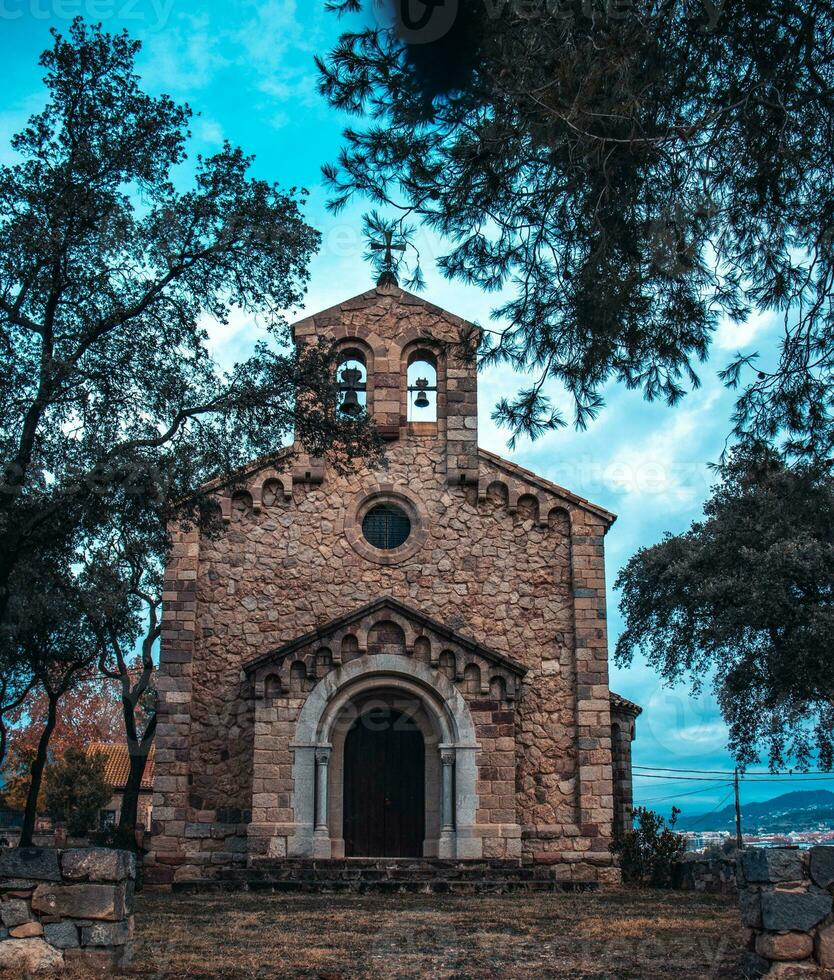 katolik kyrka belägen i catalonia grannskap. röd tegel byggnad omgiven förbi träd. foto