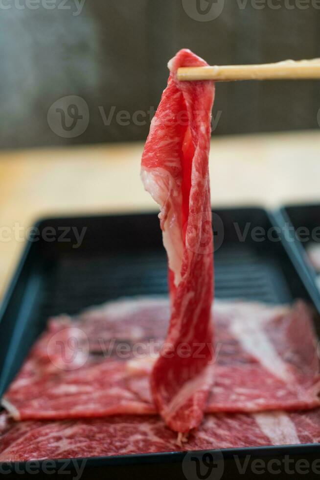 tunt skivad rå nötkött nötkreatur ras, ätpinnar är plockning upp de nötkött skivor. foto