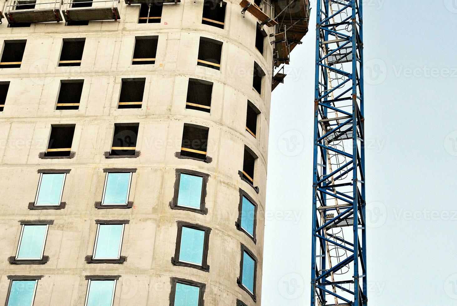 hög stiga byggnad under konstruktion. installation av glas Fasad paneler på en förstärkt betong strukturera. foto