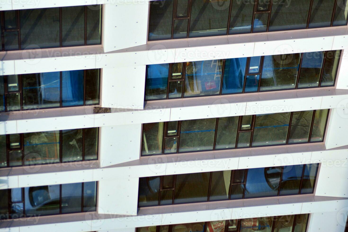 abstrakt närbild av de glasklädd Fasad av en modern byggnad täckt i reflekterande tallrik glas. arkitektur abstrakt bakgrund. glas vägg och Fasad detalj. foto