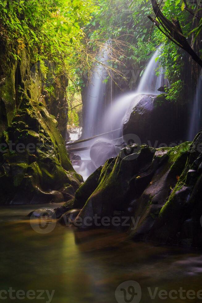 besök de charm av indonesien med de lorong vadu vattenfall, norr bengkulu. en smal gränd fodrad med sten väggar, de morgon- ljus lyser på de vattenfall foto