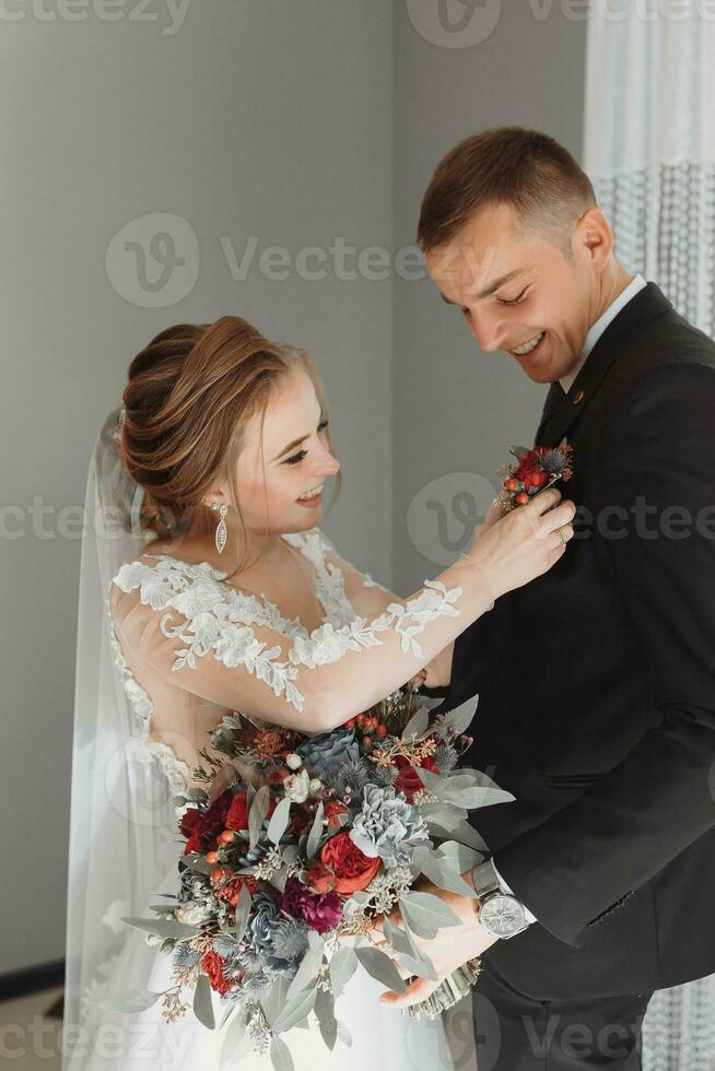 brud klamrar sig fast till de jacka av de brudgummens boutonniere av färsk blommor foto