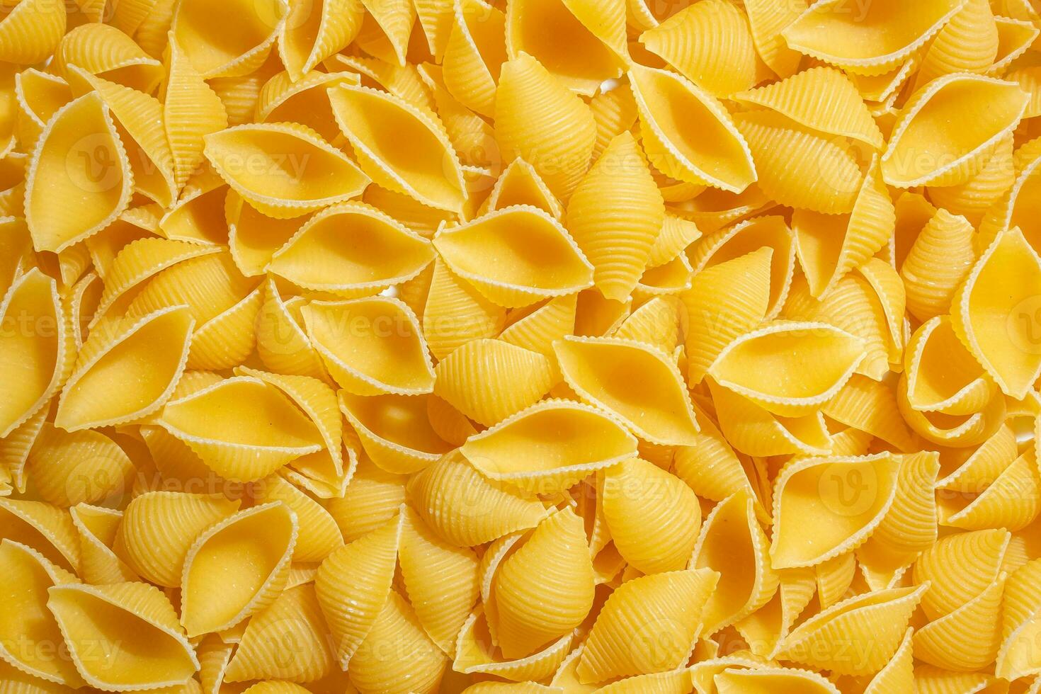 okokt conchiglie pasta. en kulinariska duk av conchiglie makaroner, skapande en livlig och texturerad bakgrund för gourmet matlagning. torr pasta. rå makaroner - topp se, platt lägga foto