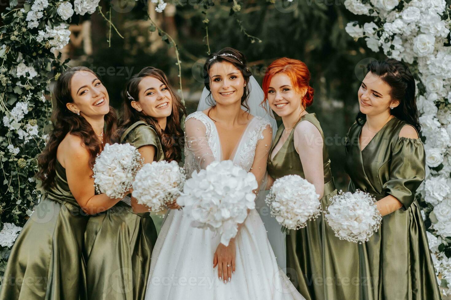 brudtärnor leende tillsammans med de brud. de brud och henne roligt vänner fira de bröllop efter de ceremoni i matchande klänningar. brud och vänner i natur foto