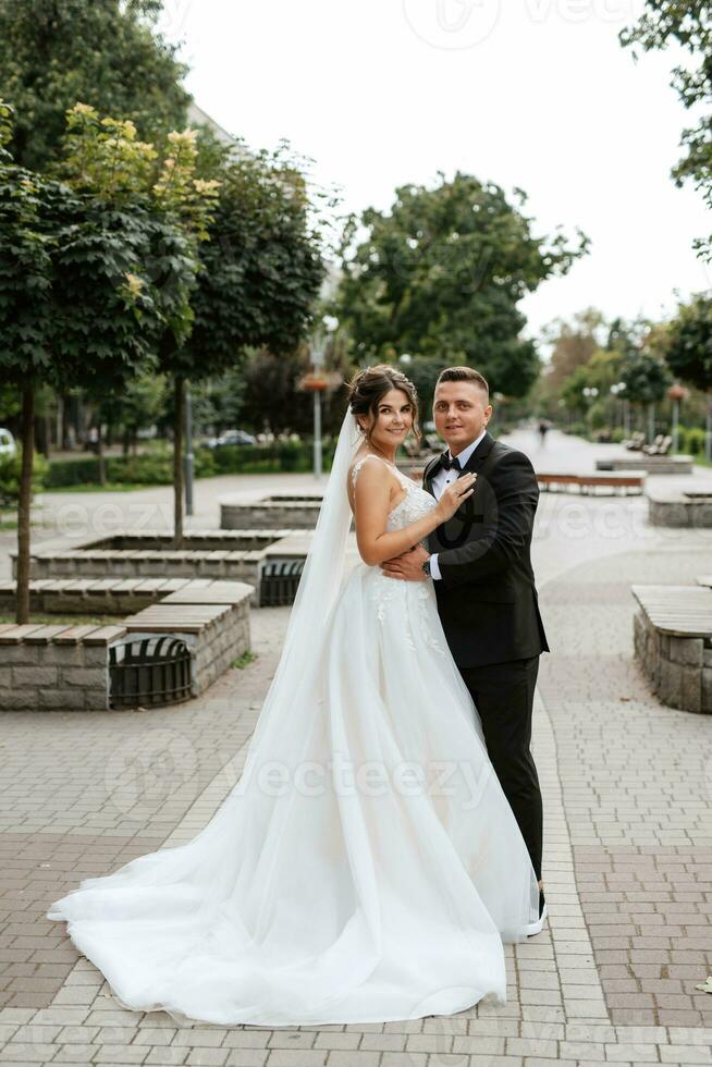 brudgummen i brun kostym och bruden i vit klänning foto