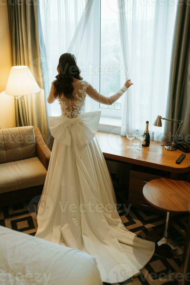 brunhårig flicka sätter på en bröllop klänning foto