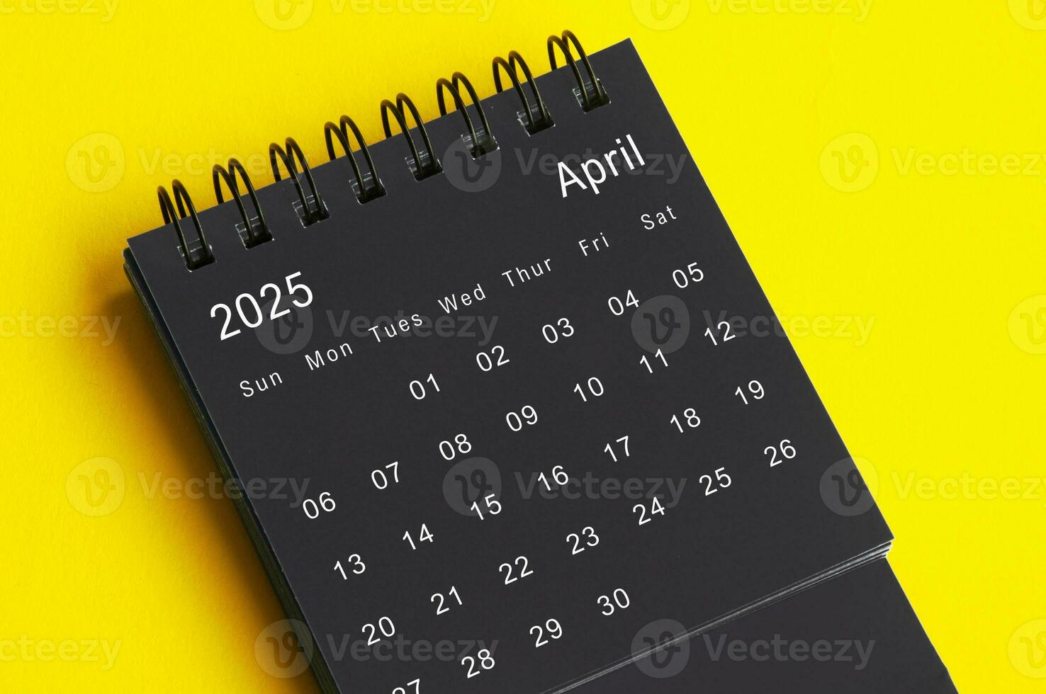 april 2025 svart och vit skrivbord kalender på gul omslag bakgrund. kalender begrepp foto