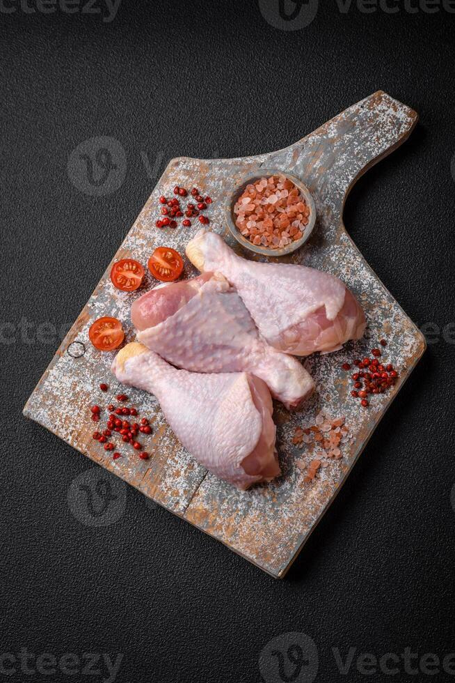 rå kyckling ben med salt, kryddor och örter på en mörk betong bakgrund foto