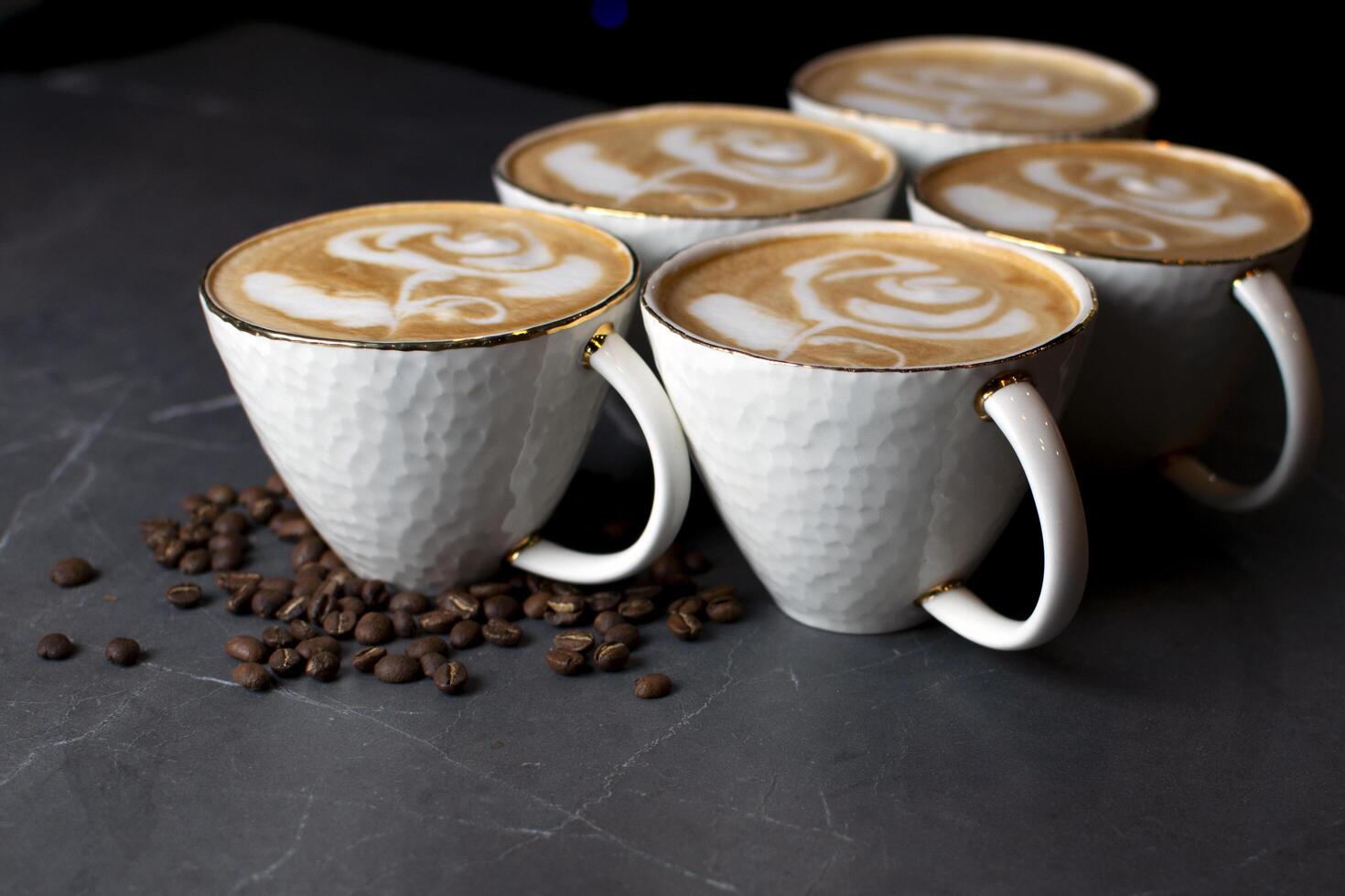 koppar kaffe står på ett marmorbord i ett kafé, lattekonst på kaffe med kaffebönor foto