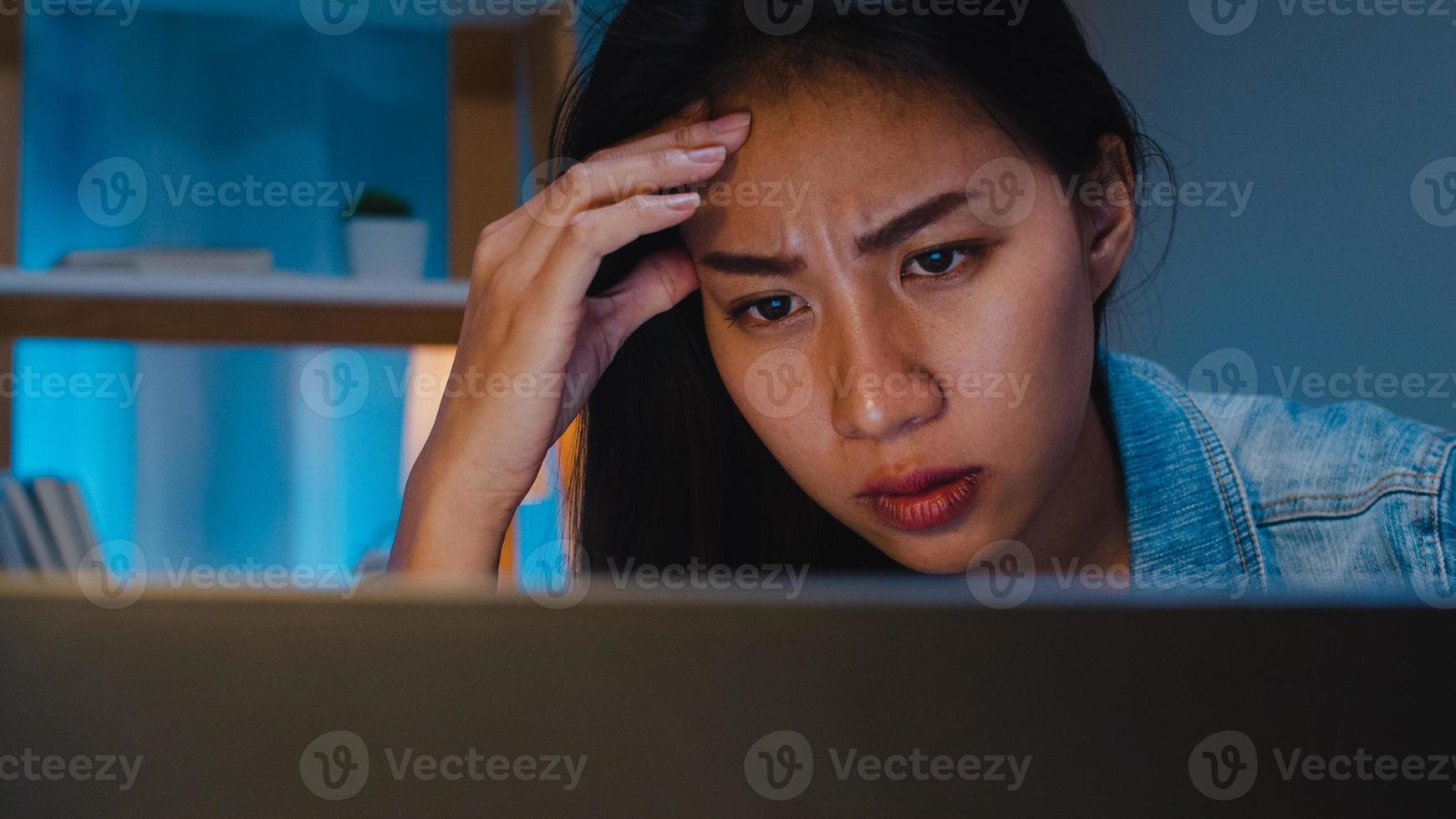 tusenårig ung kinesisk affärskvinna som arbetar sent på kvällen stressar med projektforskningsproblem på bärbar dator i vardagsrummet i modernt hem. asien människor koncept för yrkesmässig utbrändhet. foto