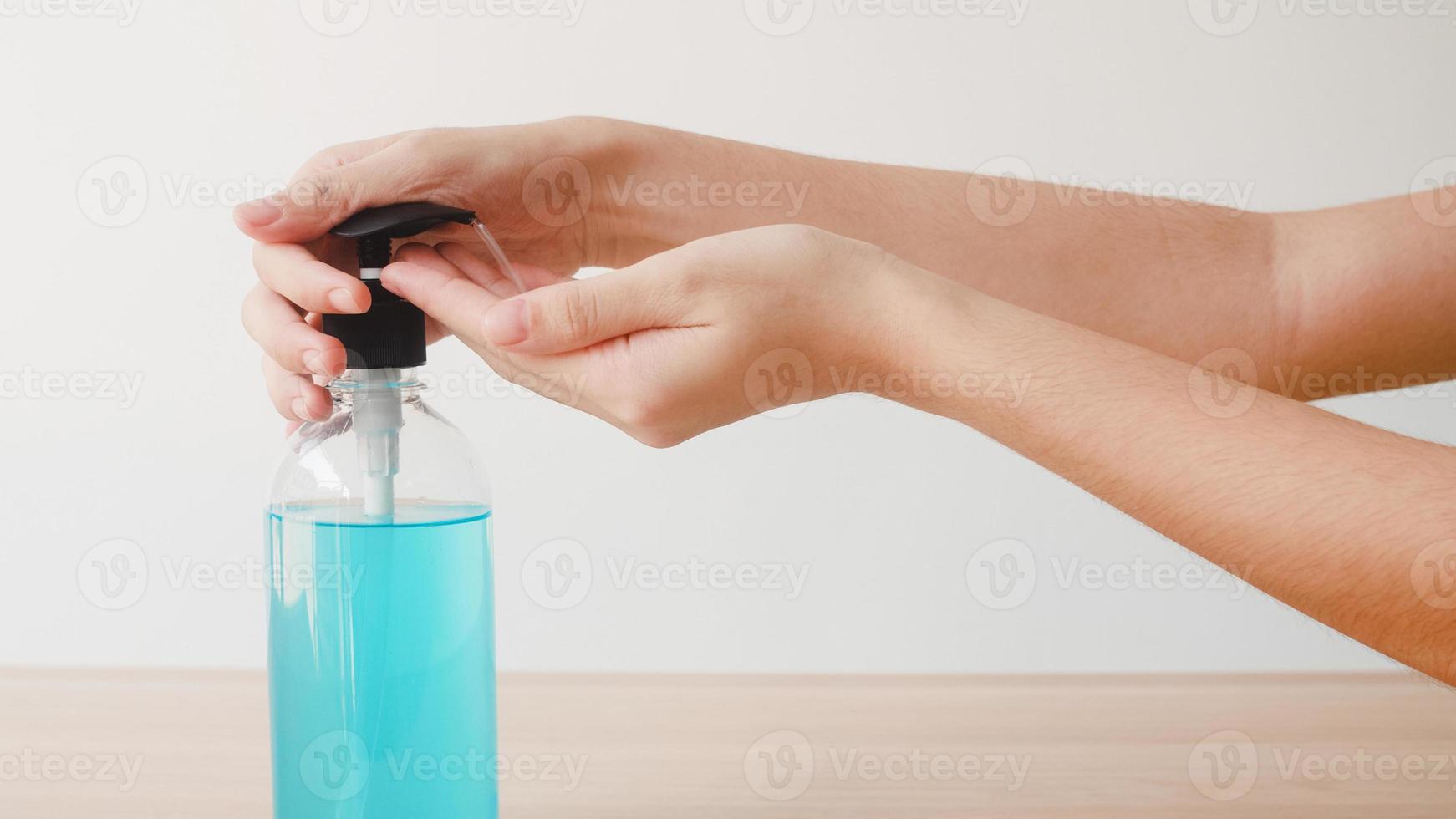 asiatisk kvinna som använder alkoholgel handsprit tvättar hand för att skydda coronaviruset. kvinnlig push -alkoholflaska för att rengöra handen för hygien när social distansering stannar hemma och självkarantänstid. foto