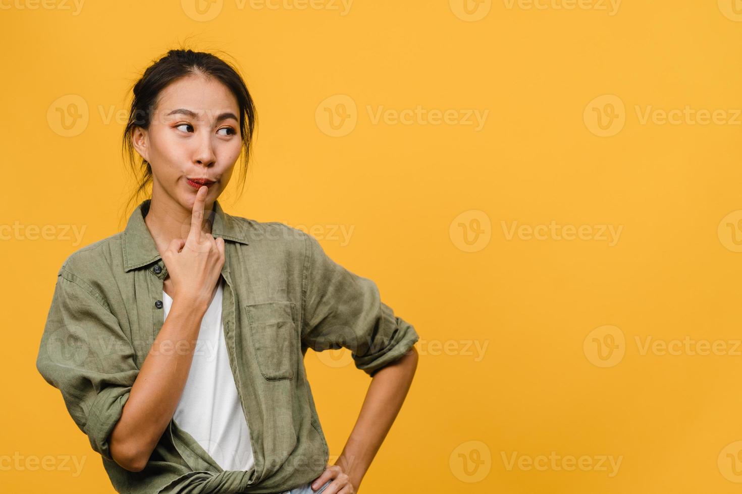porträtt av ung asiatisk dam med positivt uttryck, tänker på kommande helgdagar, klädd i vardagskläder över gul bakgrund med tomt kopieringsutrymme. glad förtjusande glad kvinna jublar över framgång. foto