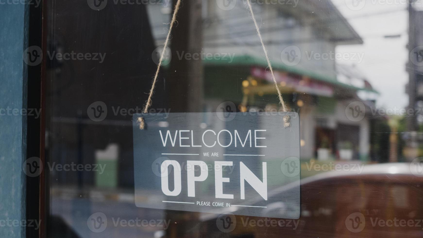 Välkommen, vi är öppna vintage svartvita retro -skyltar på ett kaffeglasdörrkafé efter karantän. ägare småföretag, mat och dryck, företag öppnar igen koncept. foto
