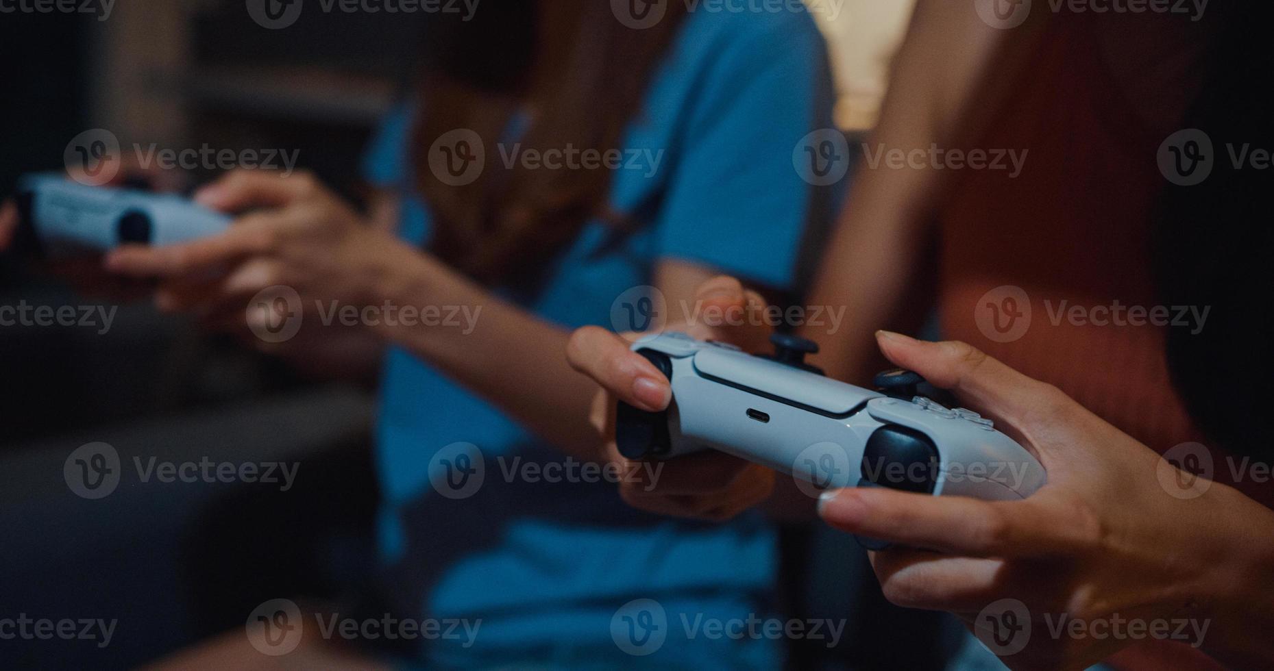 närbild fokus asien par damer hand njuta av lyckligt ögonblick använda controller gamepad spela videospel webbplats på soffan vardagsrum i hemmet vid mörk natt. helgaktivitet karantän koncept. foto