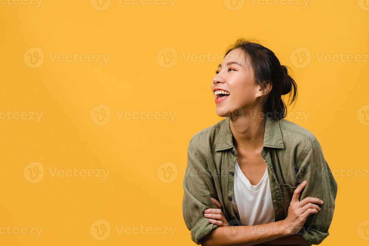 porträtt av ung asiatisk dam med positivt uttryck, korsade armen, le stort, klädd i avslappnad trasa över gul bakgrund. glad förtjusande glad kvinna jublar över framgång. ansiktsuttryck koncept. foto