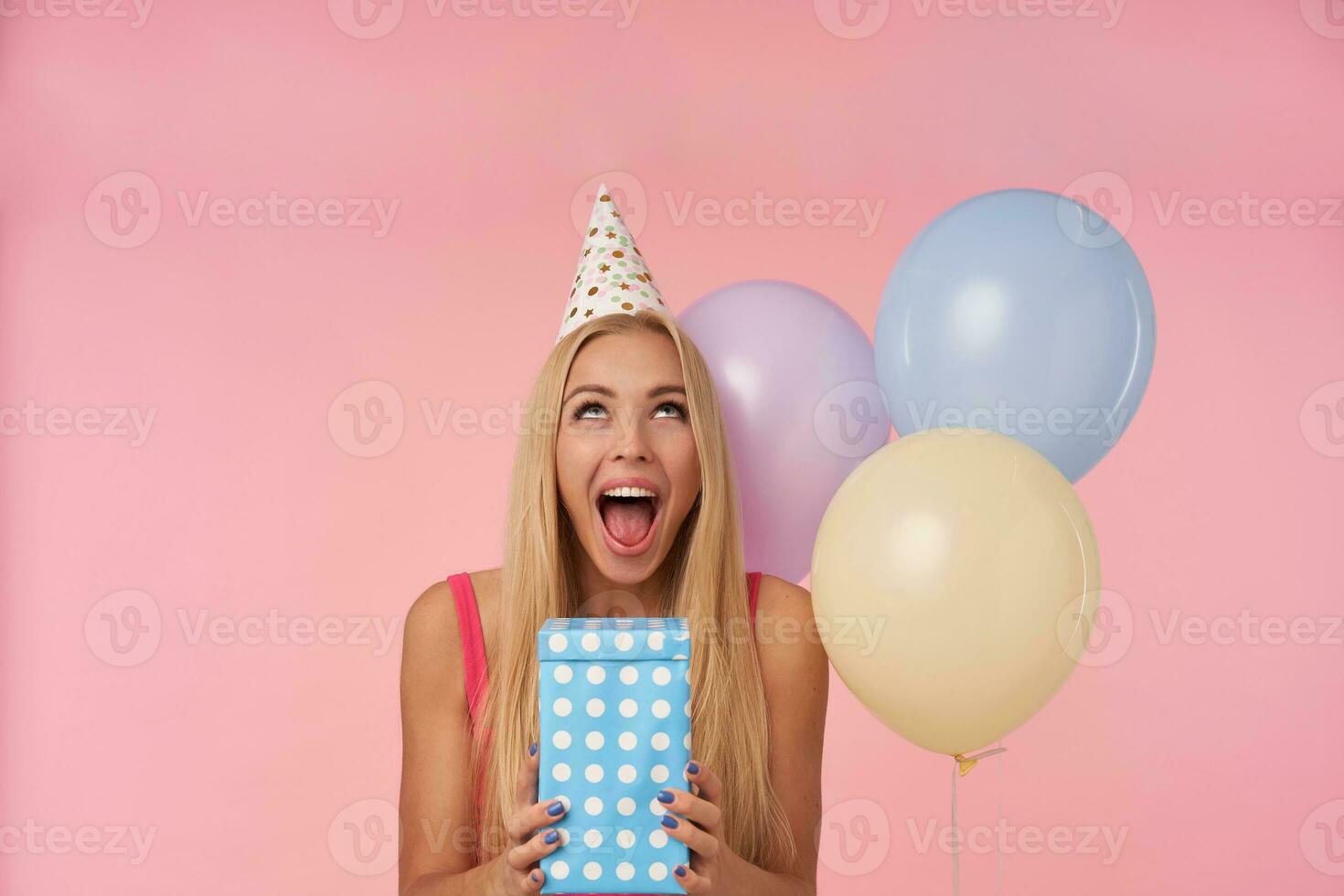 lycklig ung lång håriga blond lady varelse upphetsad och överraskad till skaffa sig födelsedag presenterar, har glad stunder i henne liv under födelsedag fest, Framställ över rosa bakgrund foto