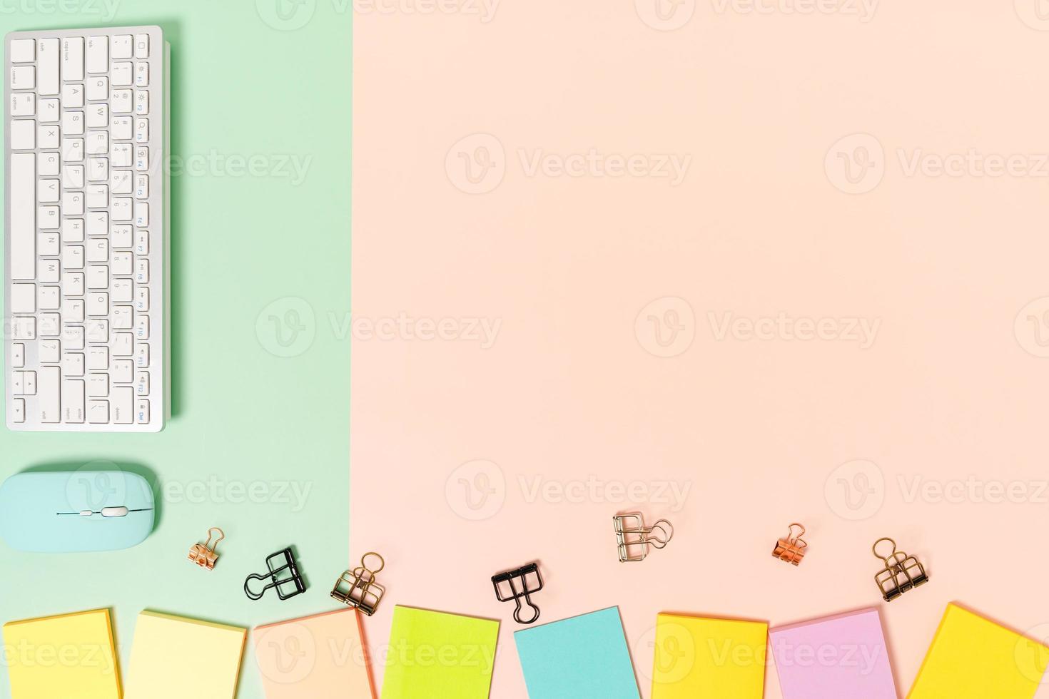 minimalt arbetsutrymme - kreativt plattläggningsfoto av arbetsytans skrivbord. ovanifrån kontorsbord med tangentbord, mus och självhäftande anteckning på pastellgrön rosa bakgrund. ovanifrån med fotografering av kopieringsutrymme. foto