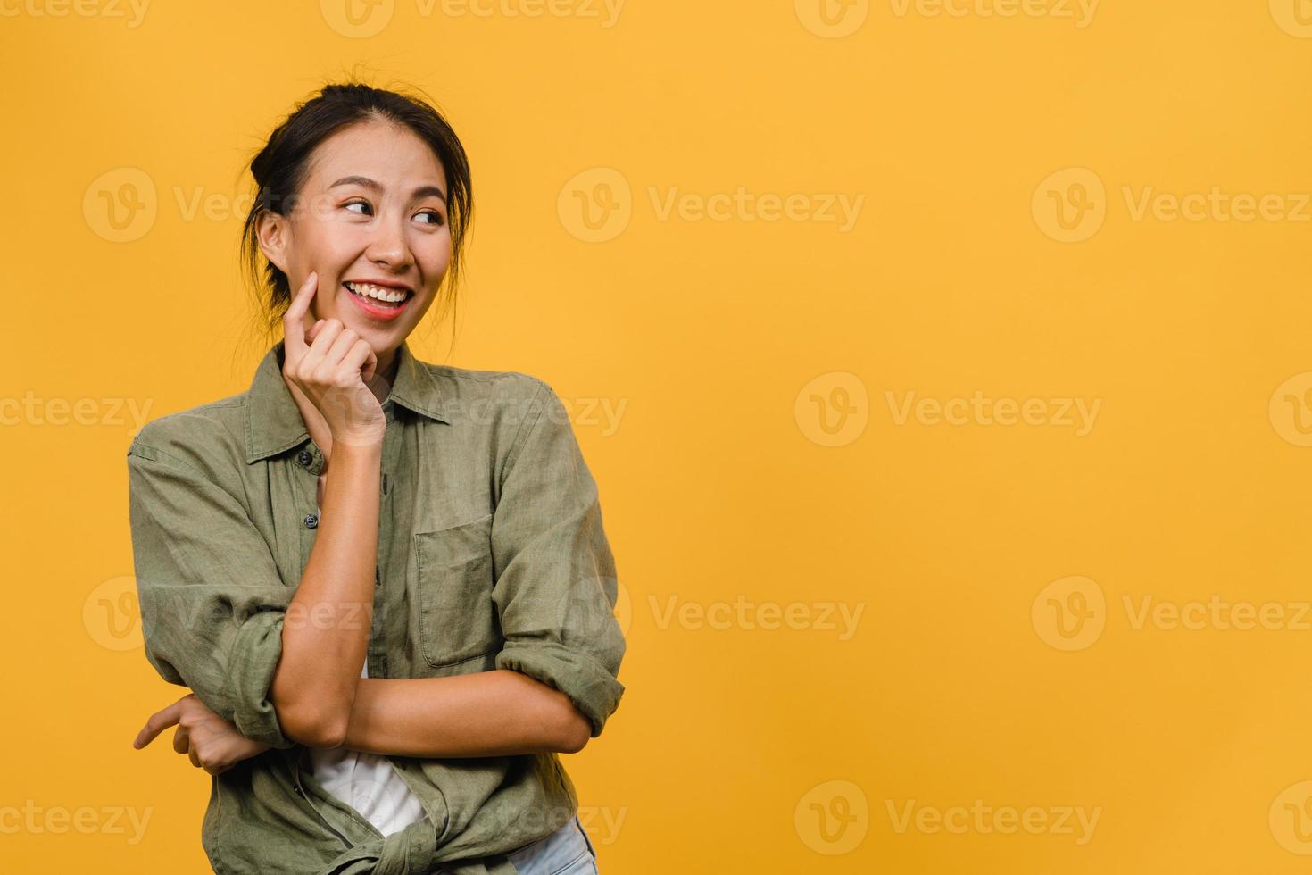 porträtt av ung asiatisk dam med positivt uttryck, korsade armen, le stort, klädd i avslappnad trasa över gul bakgrund. glad förtjusande glad kvinna jublar över framgång. ansiktsuttryck koncept. foto