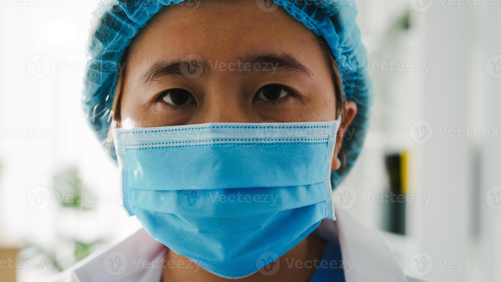 ung asiatisk damläkare eller sjuksköterska arbetskirurg förbereder sig för kirurgisk operation och trött öppnar ögonen och tittar på kameran på hälsosjukhusets kontor. social distansering, karantän för coronavirus. foto