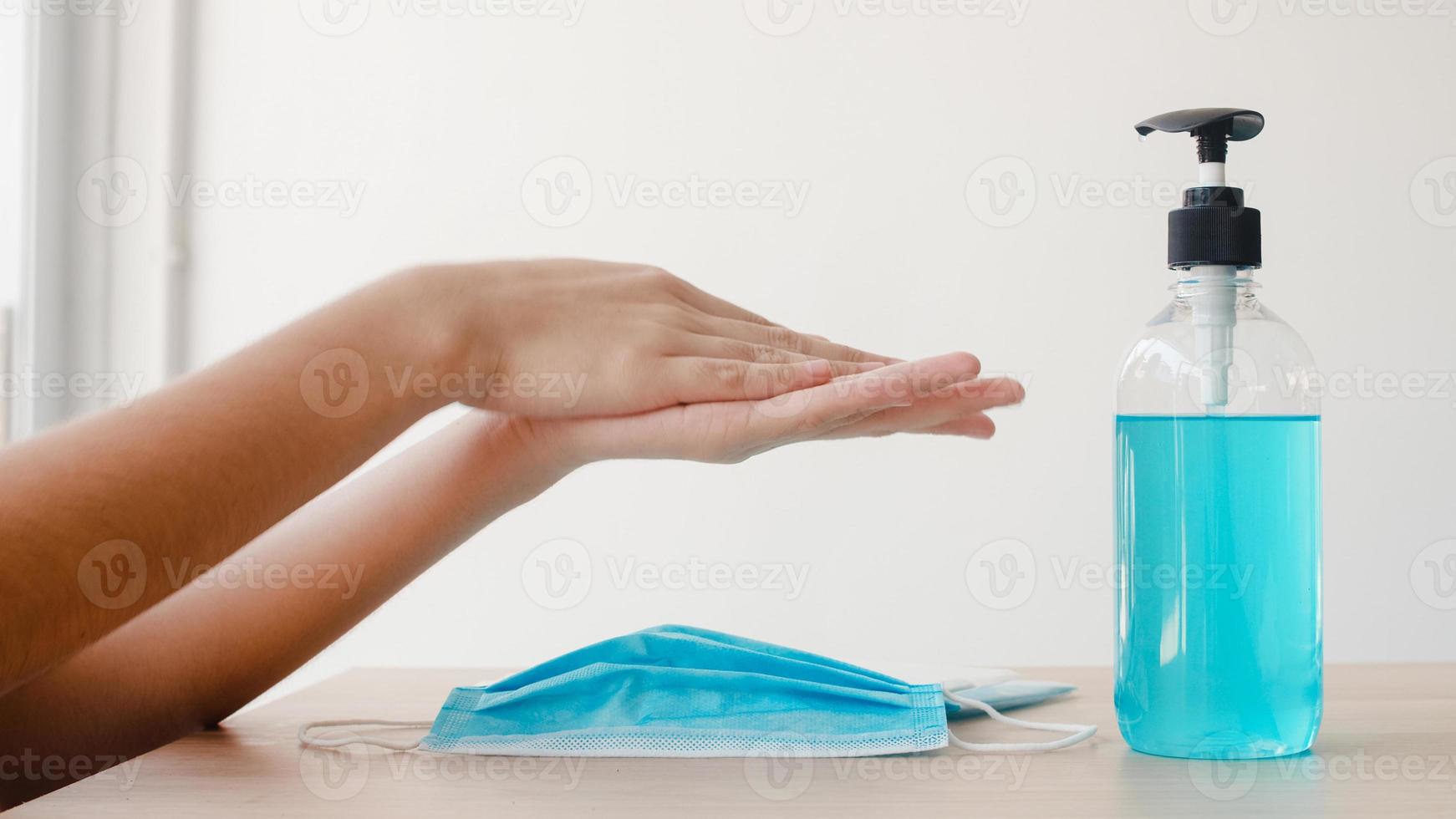 asiatisk kvinna som använder alkoholgel handdesinfektionsmedel, tvätta handen innan du bär mask för att skydda coronaviruset. kvinnor pressar alkohol för att städa för hygien när social distans stannar hemma och självkarantän. foto