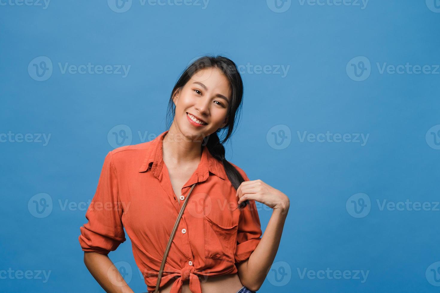 ung asiatisk dam med positivt uttryck, le brett, klädd i vardagskläder och titta på kameran över blå bakgrund. glad förtjusande glad kvinna jublar över framgång. ansiktsuttryck koncept. foto