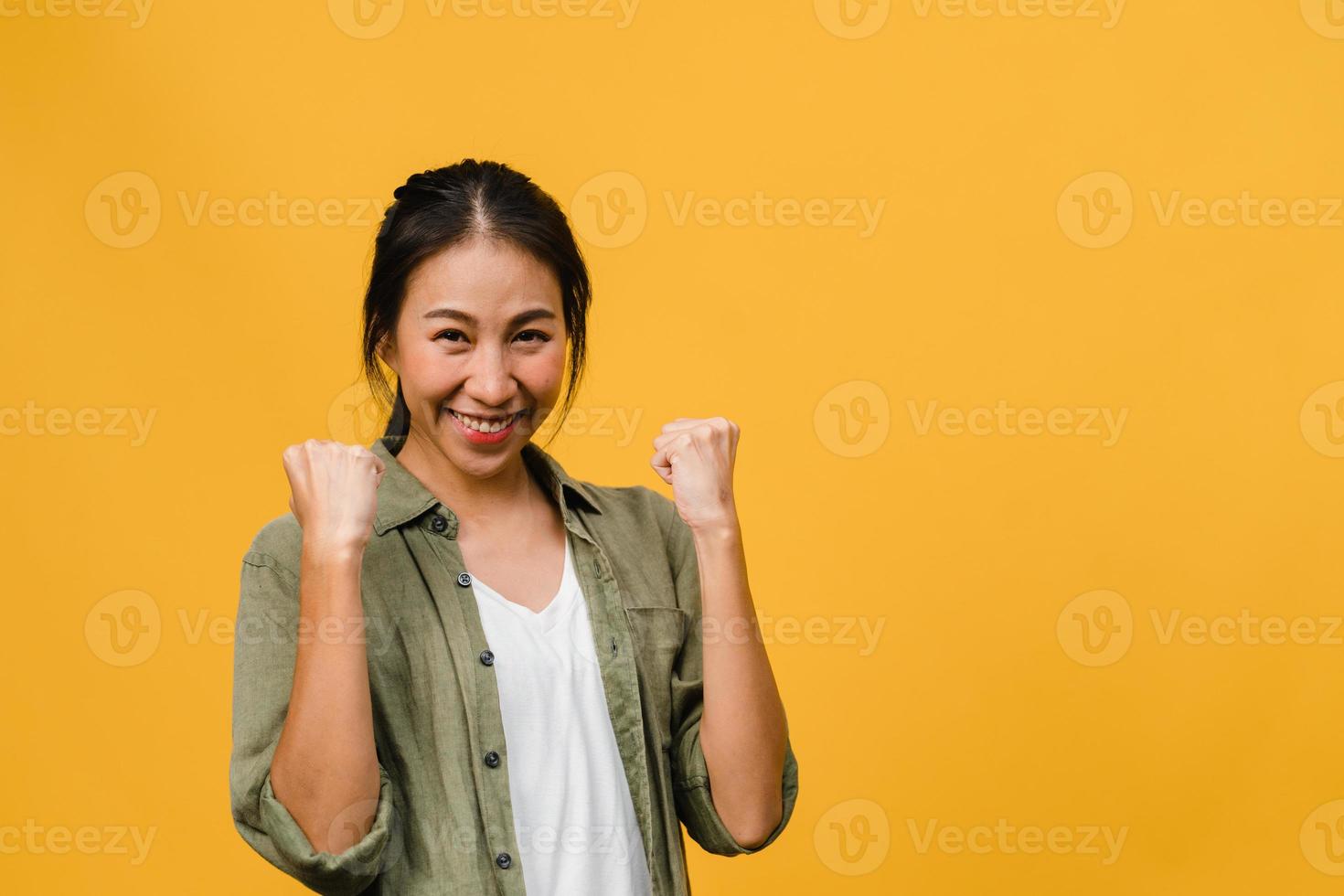 ung asiatisk dam med positivt uttryck, glad och spännande, klädd i vardagsduk och titta på kameran över gul bakgrund. glad förtjusande glad kvinna jublar över framgång. ansiktsuttryck koncept. foto